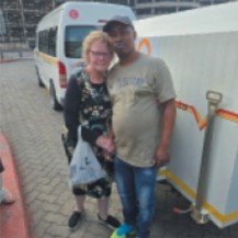 Rose standing beside a friend in front of a white van in South Africa